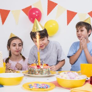 friends clapping while boy cutting his birthday cake home