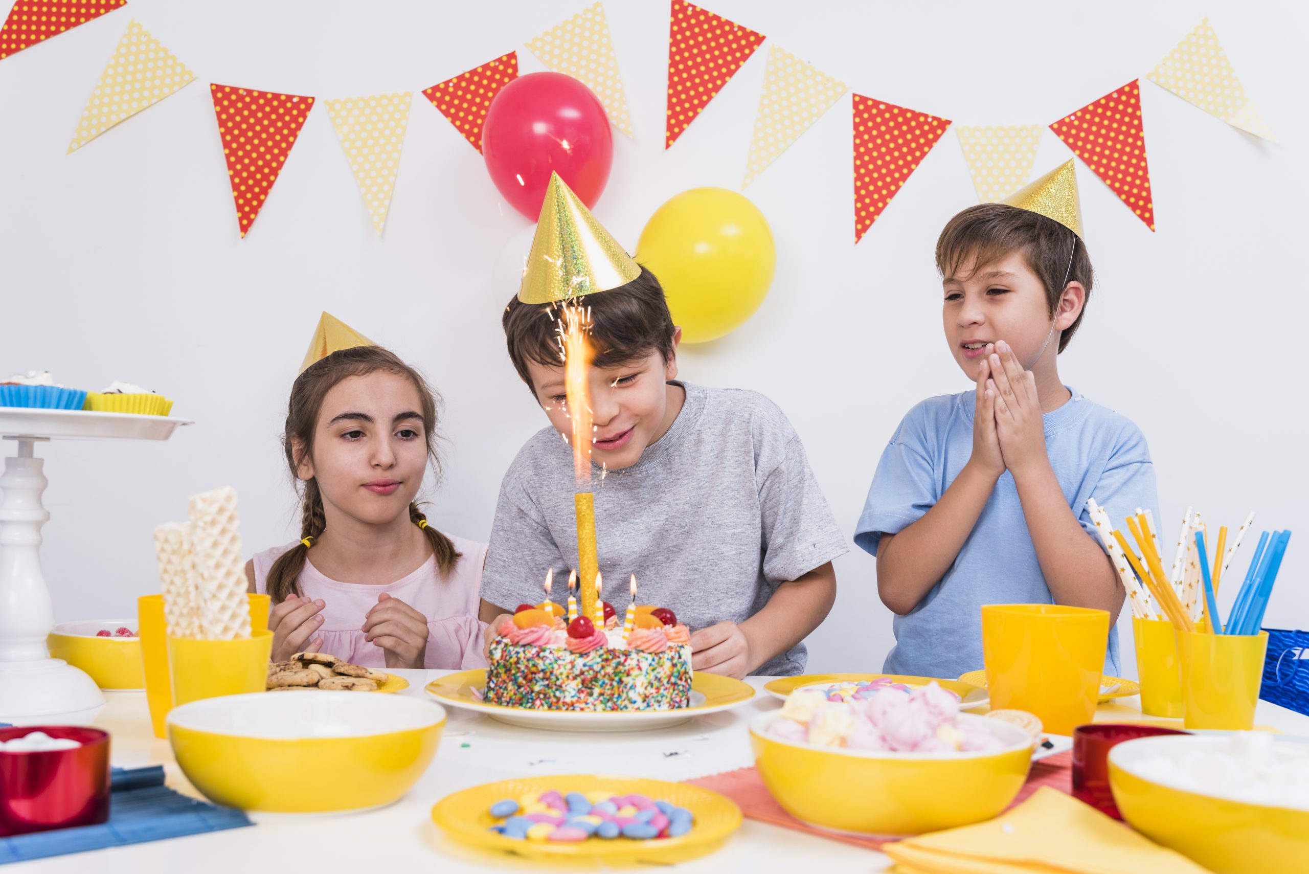 friends clapping while boy cutting his birthday cake home