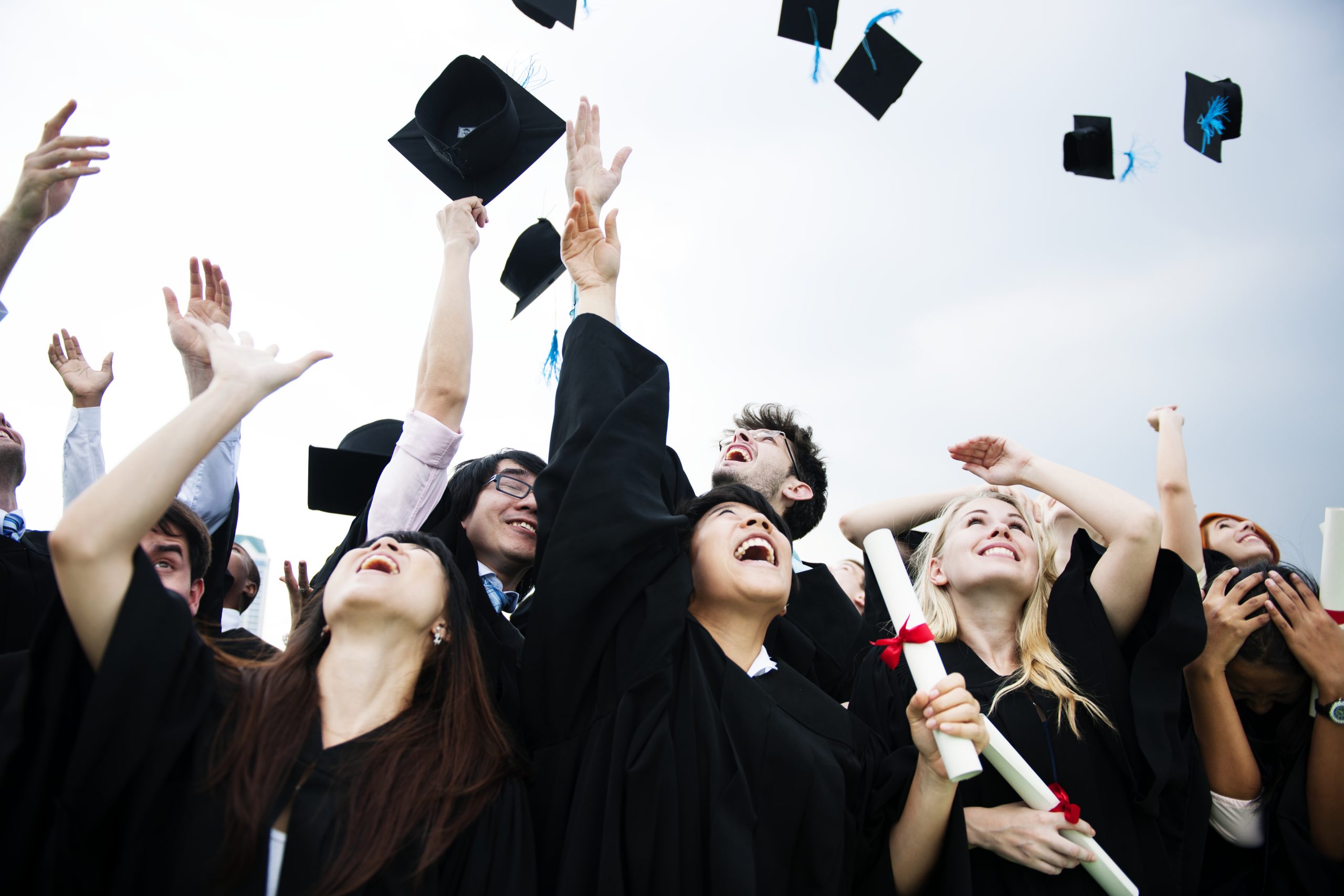 group of diverse grads throwing caps up in the sky